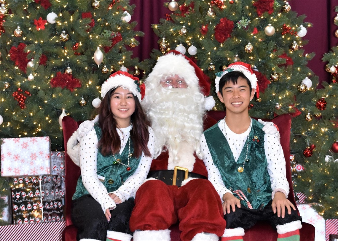 Santa sitting with two elves