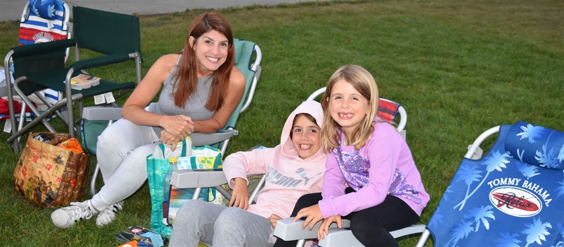 Smiling people in beach chairs waiting to watch an outdoor movie